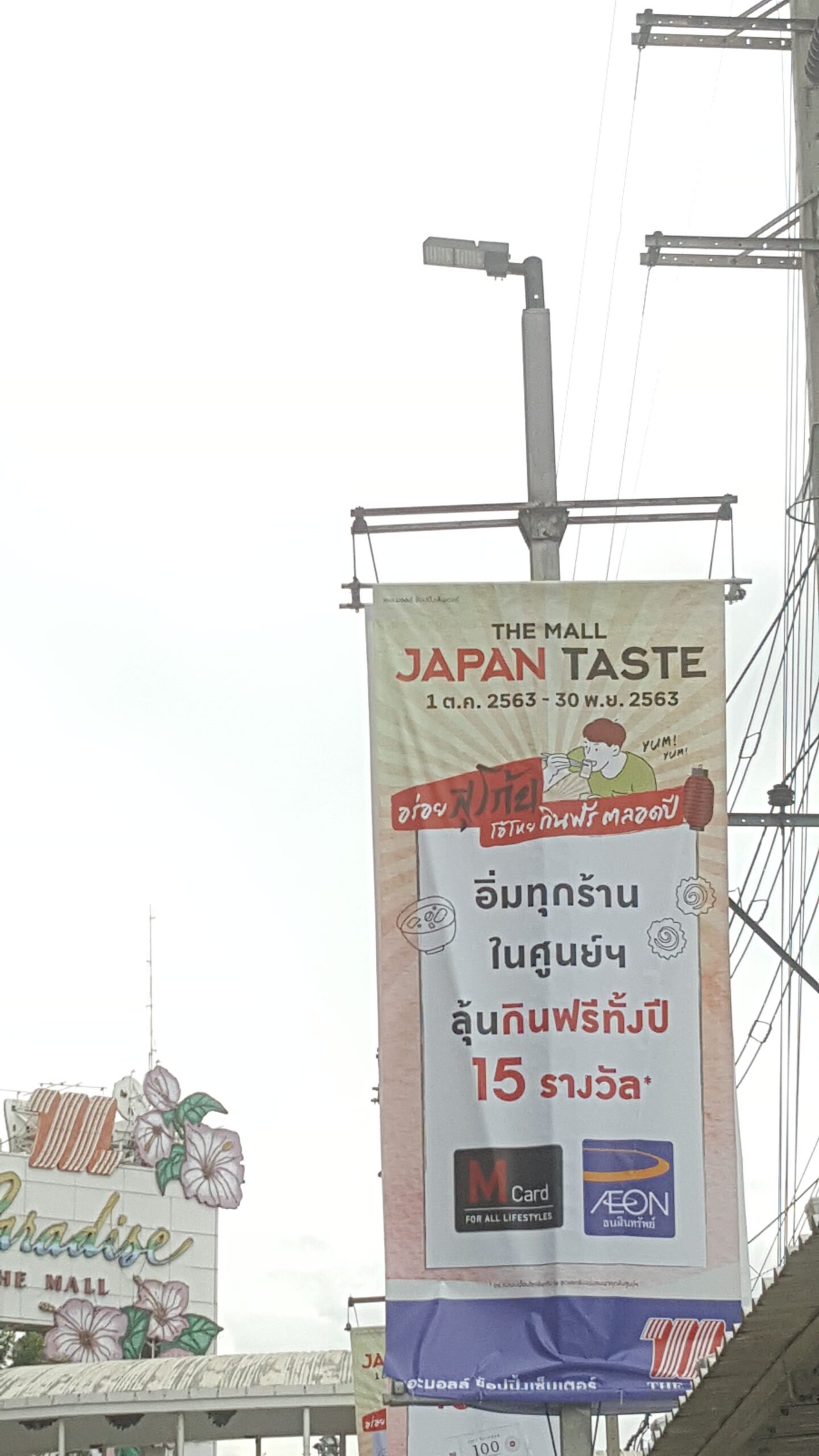 Daytime view of Galaxy LED street light installed in 2020 on a Thai commercial street with advertising banners